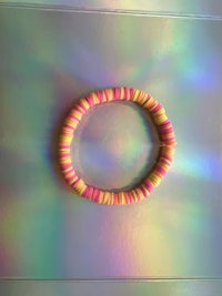 a pink and yellow bracelet on a rainbow surface