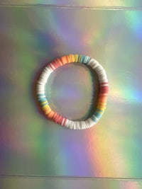 a rainbow colored bracelet on a holographic surface